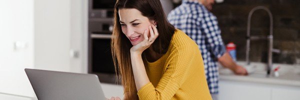 Woman stood at kitchen counter with laptop smiling | residential mortgages