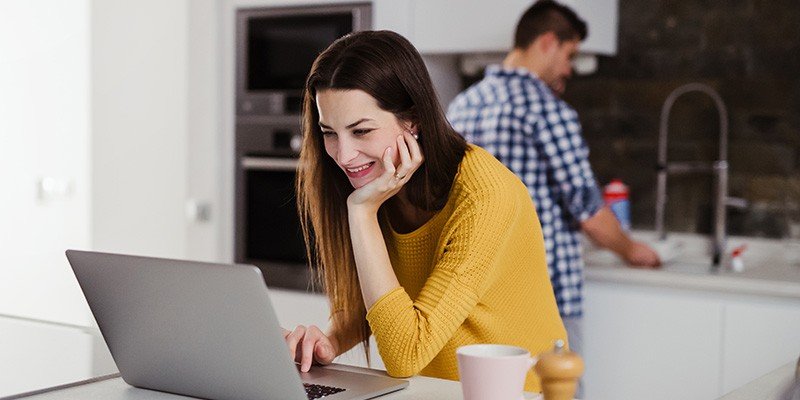 Woman stood at kitchen counter with laptop smiling | residential mortgages