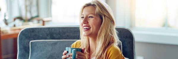 Young woman sat in an armchair smiling to represent Expat Residential case study