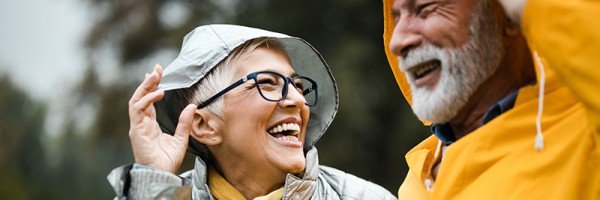 Close up of an older couple smiling outdoors wearing raincoats | Lending into retirement mortgage case study