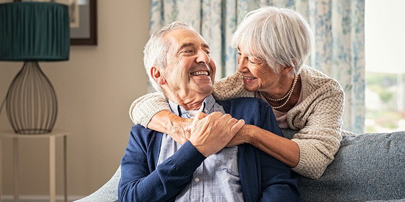 An old couple smiling and hugging in their home after receiving help with a Later Life mortgage from Marsden Intermediaries