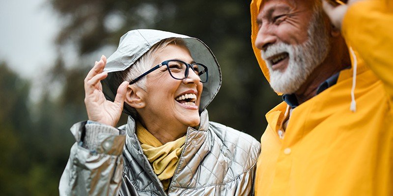 Close up of an older couple smiling outdoors wearing raincoats | Lending into retirement mortgage case study